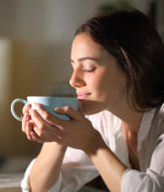 Imagem de mulher cheirando uma caneca com chá.